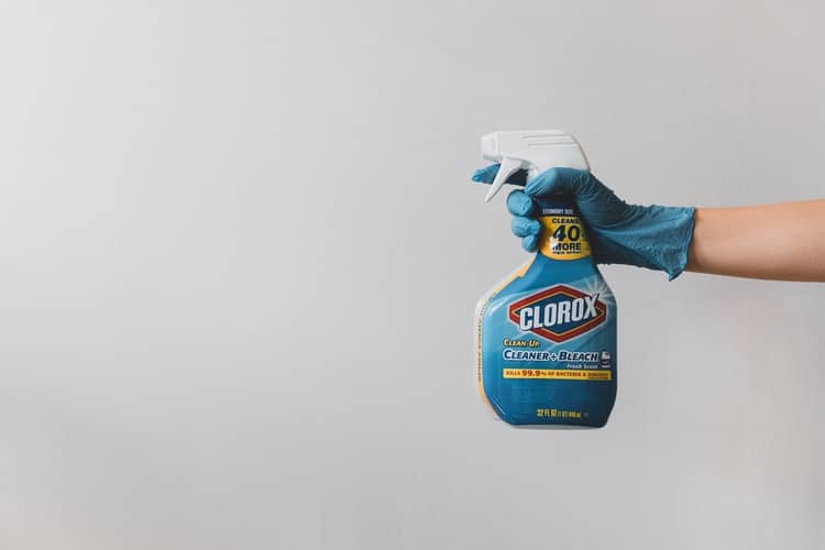 Person spraying bleach cleaner