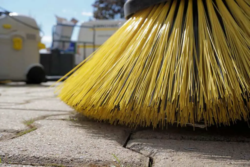 Cleaning the bird poop off concrete with a broom