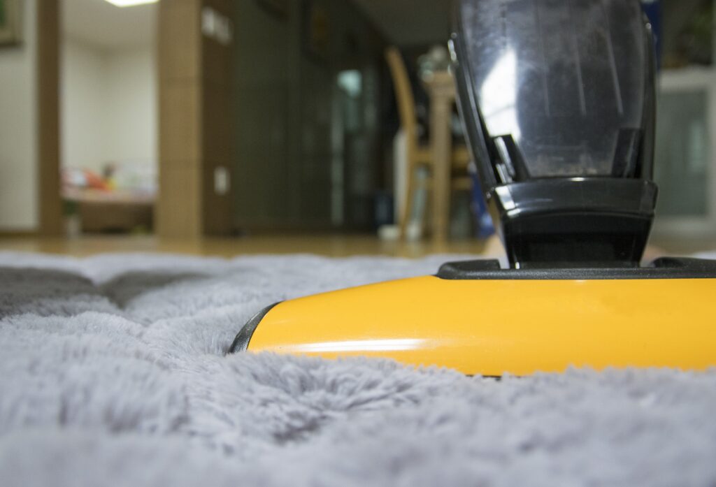 A close up shot of a yellow vacuum cleaner on a rug