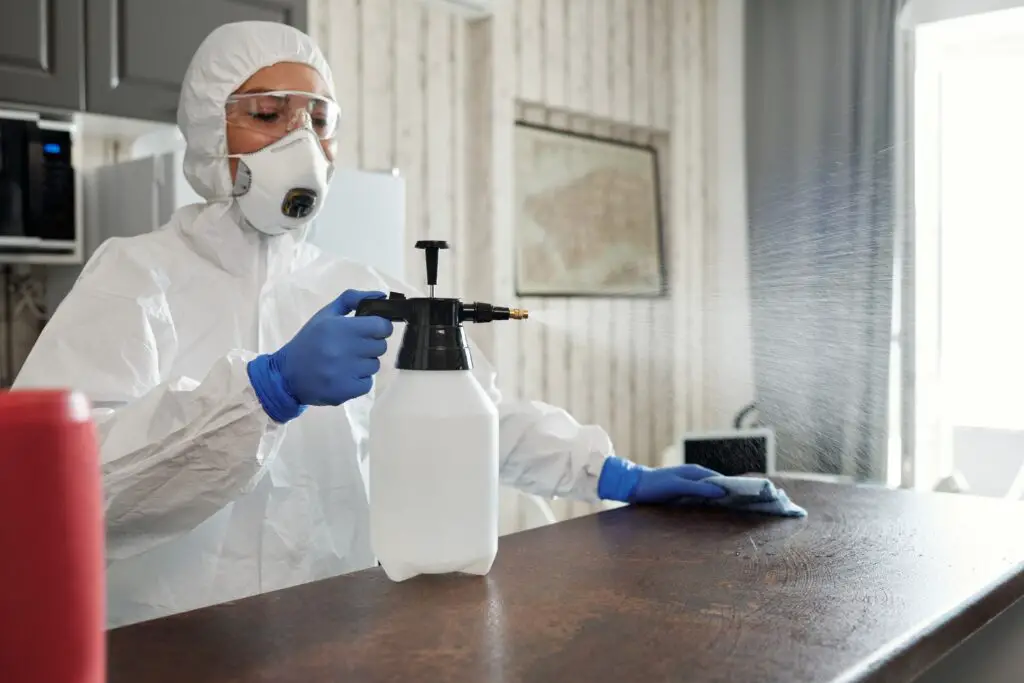 A person wearing protective equipment while spraying a disinfectant