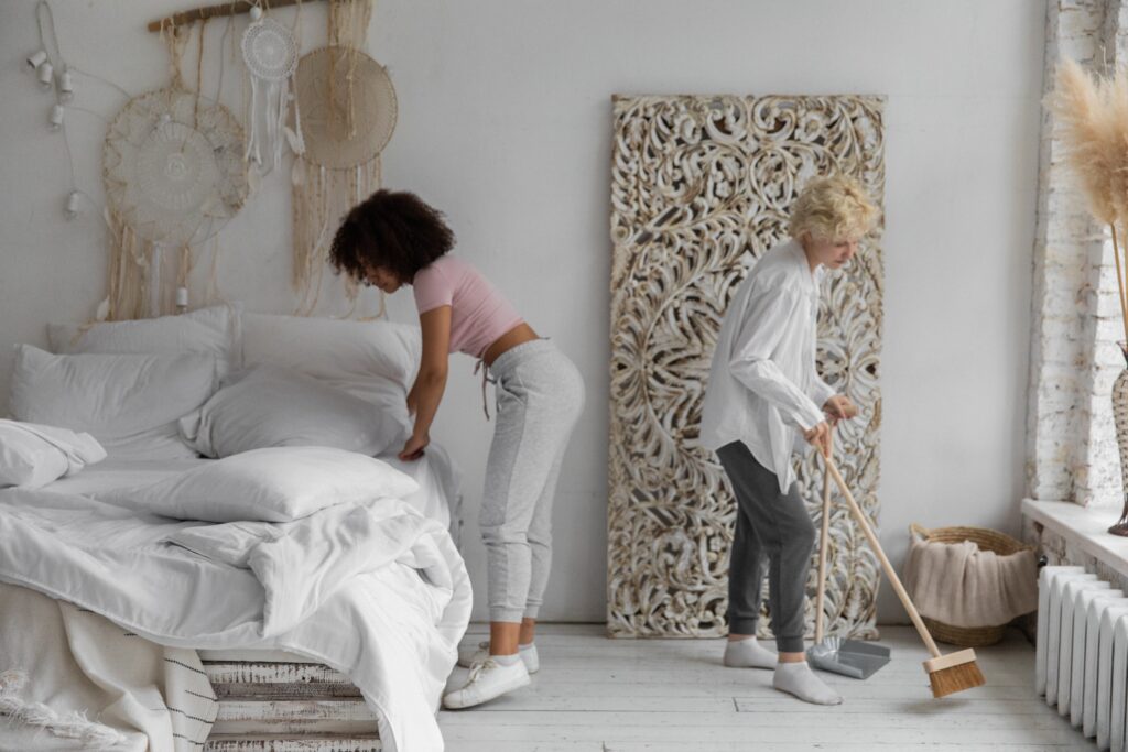 Two persons cleaning together a messy room