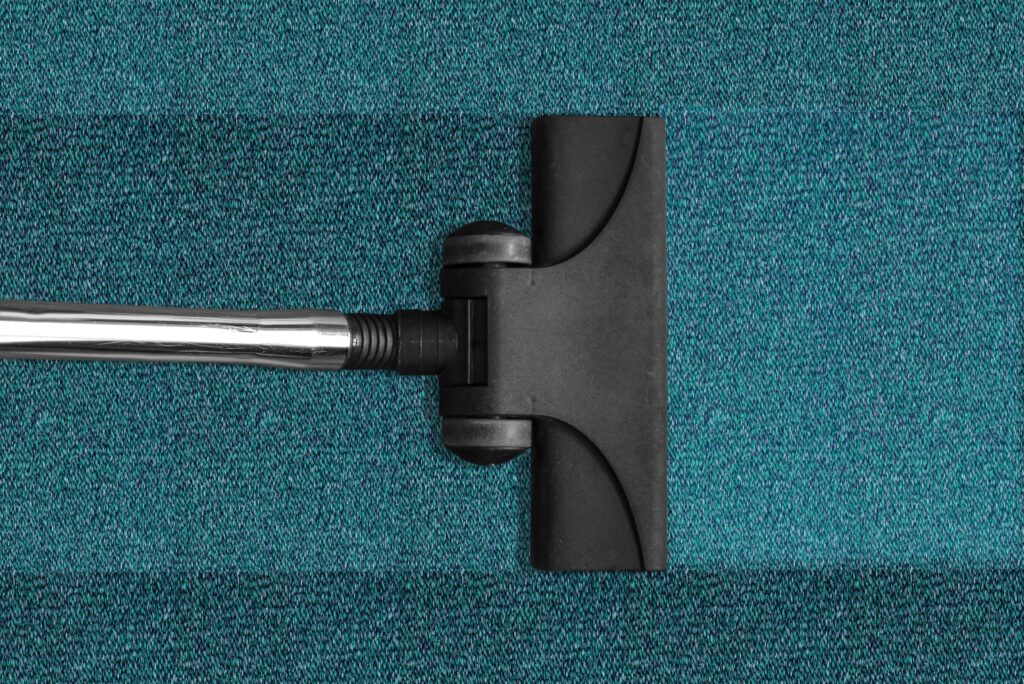 Removing dust and dirt on a blue carpet with a cleaner