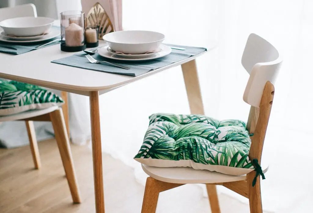 A wooden dining table with a dining chair and a separate cushion