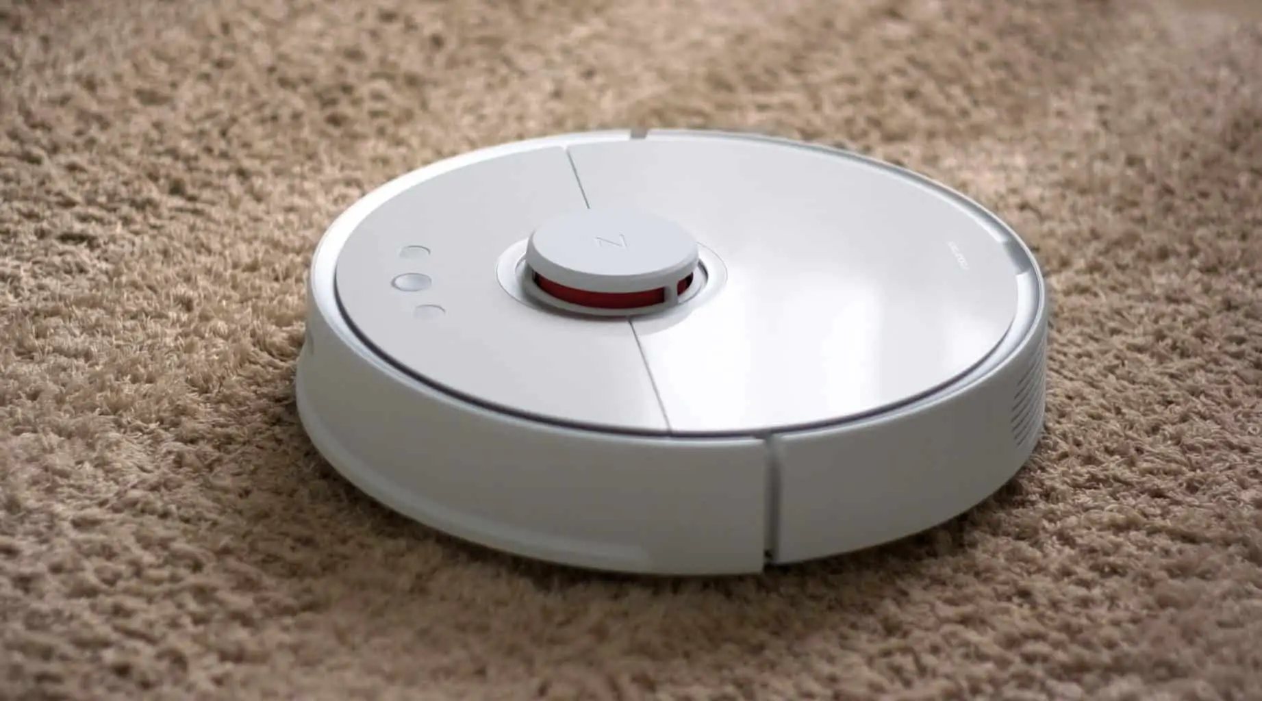 A white robot vacuum on a rug