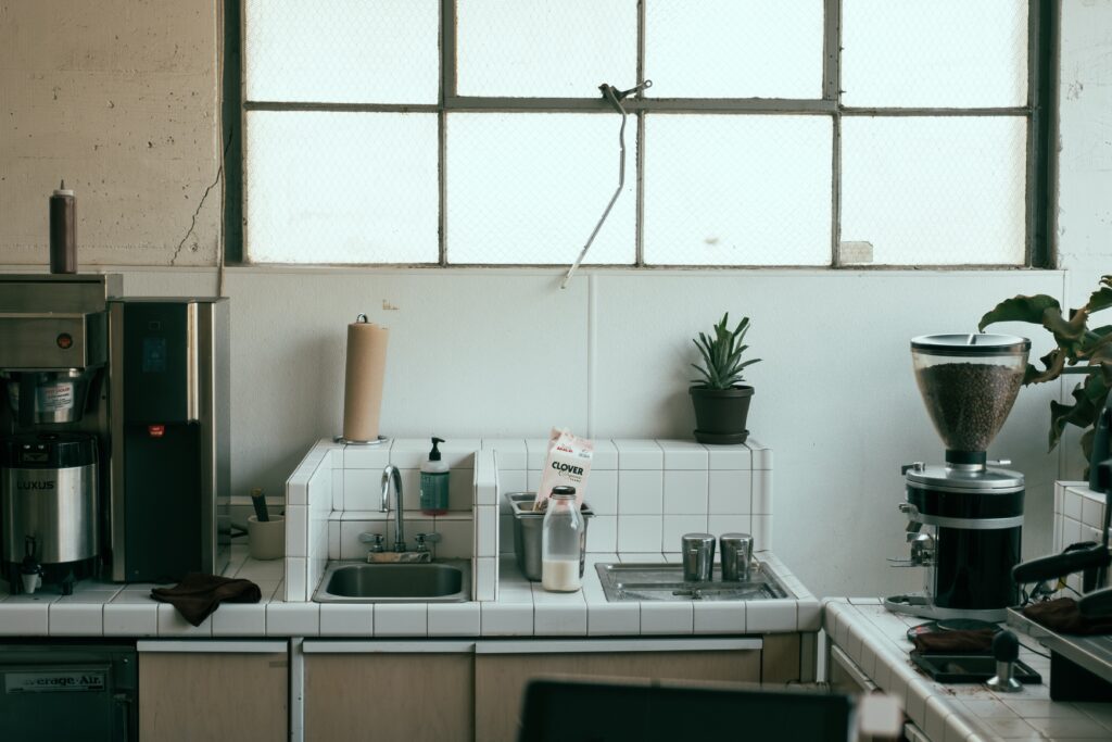 A messy kitchen countertop with white small tles and coffeemaker