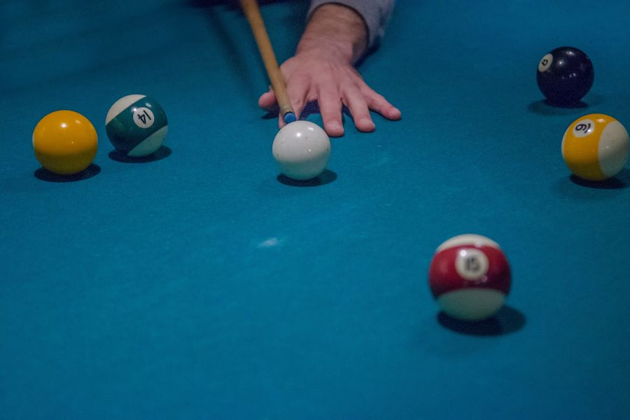 Person aiming the cue stick to hit a ball