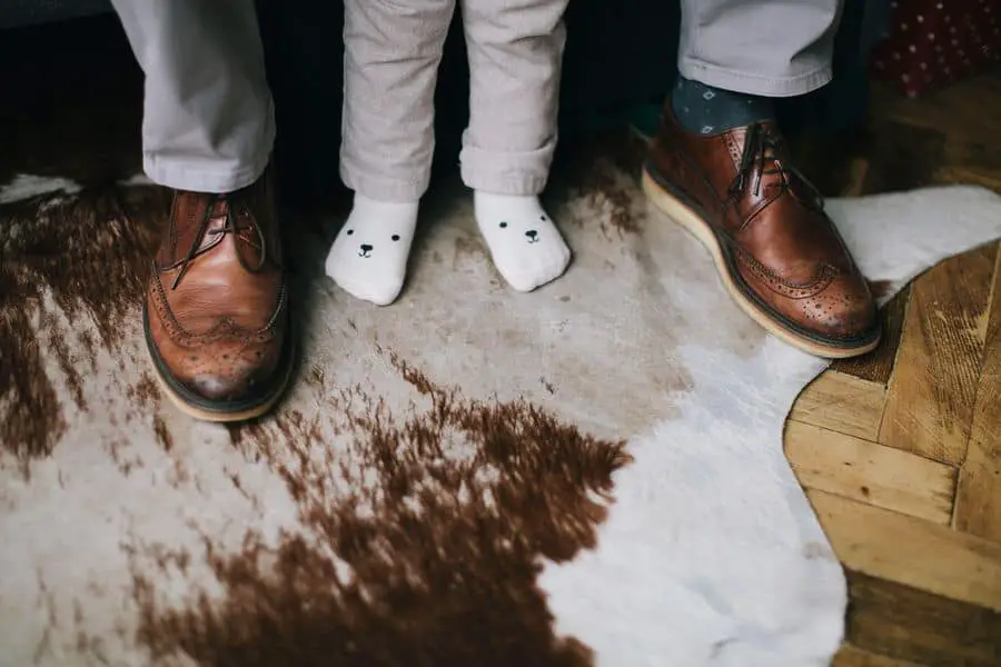 Closeup of people's feet stepping on a clean cowhide rug
