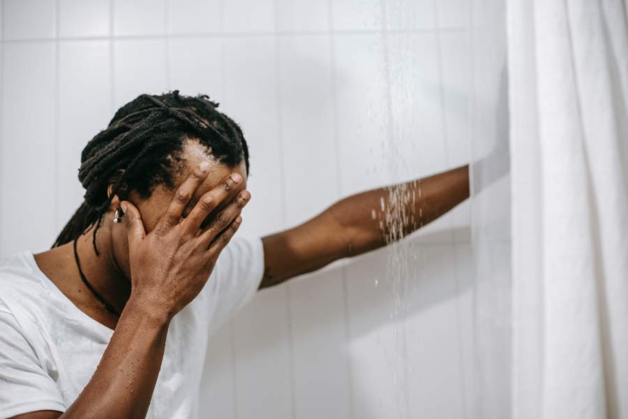 Un hombre lavando sus rastas en la ducha