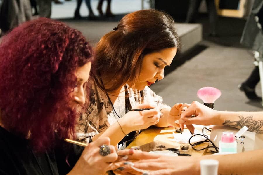 Two women doing nail art by using acrylic nail brush