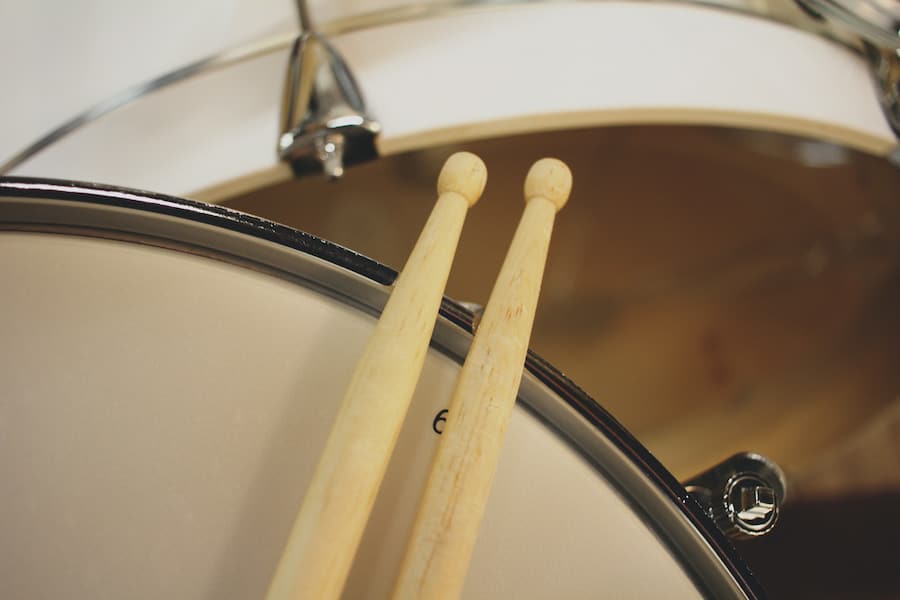 Two beige drum sticks on top of a drum head