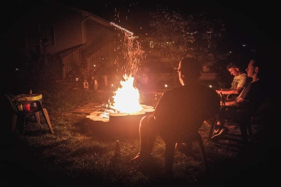 Three men in front of a firepit