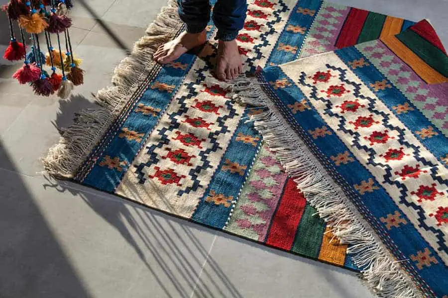 Person in blue denim jeans on top of the kilim rug