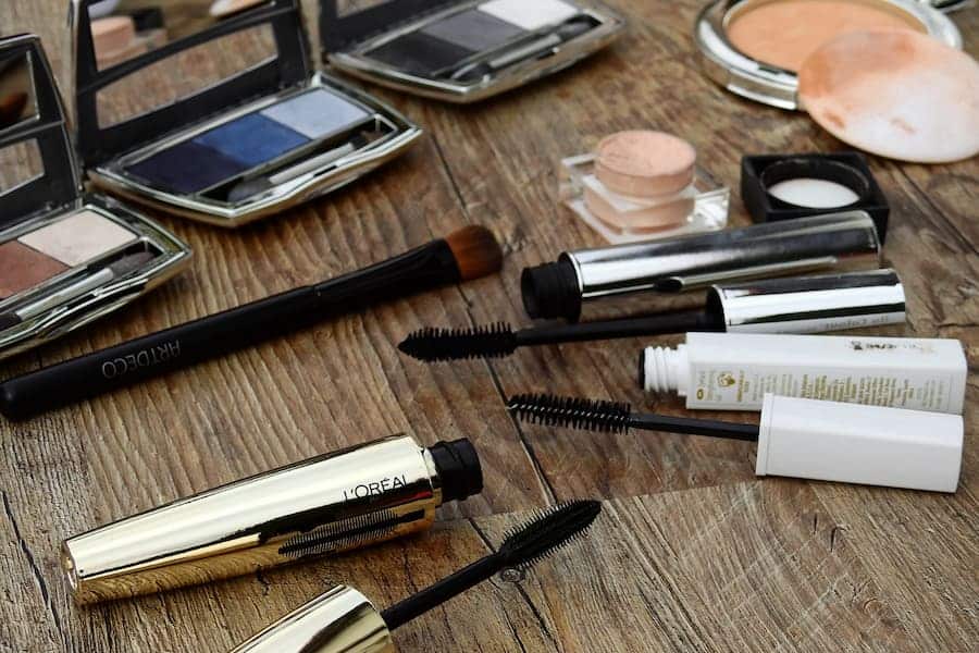 Mascara tube and other make up on a wooden table.