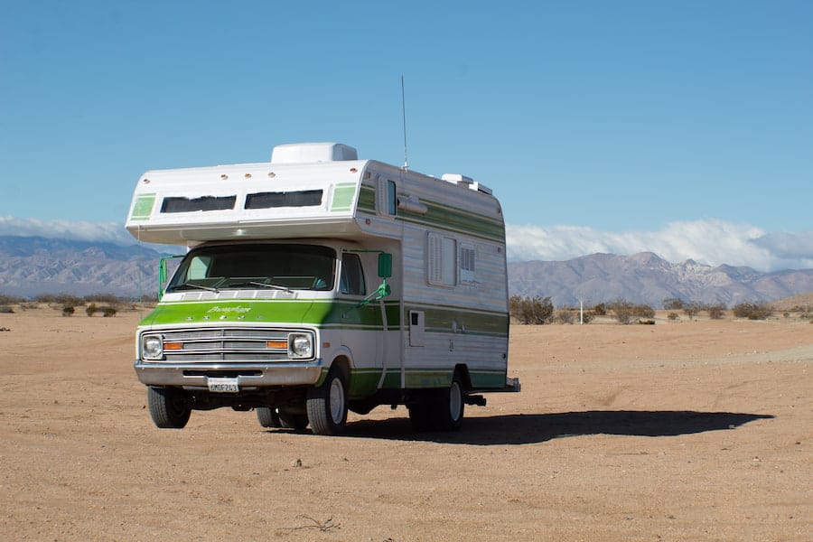 White and green RV on a brown field