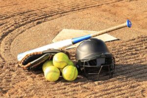 An image of a clean softball bat with helmet and ball