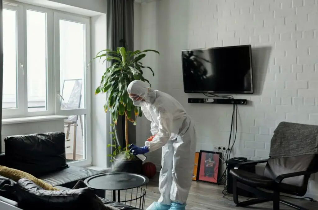 Persona que usa un desinfectante y usa equipo de protección mientras limpia