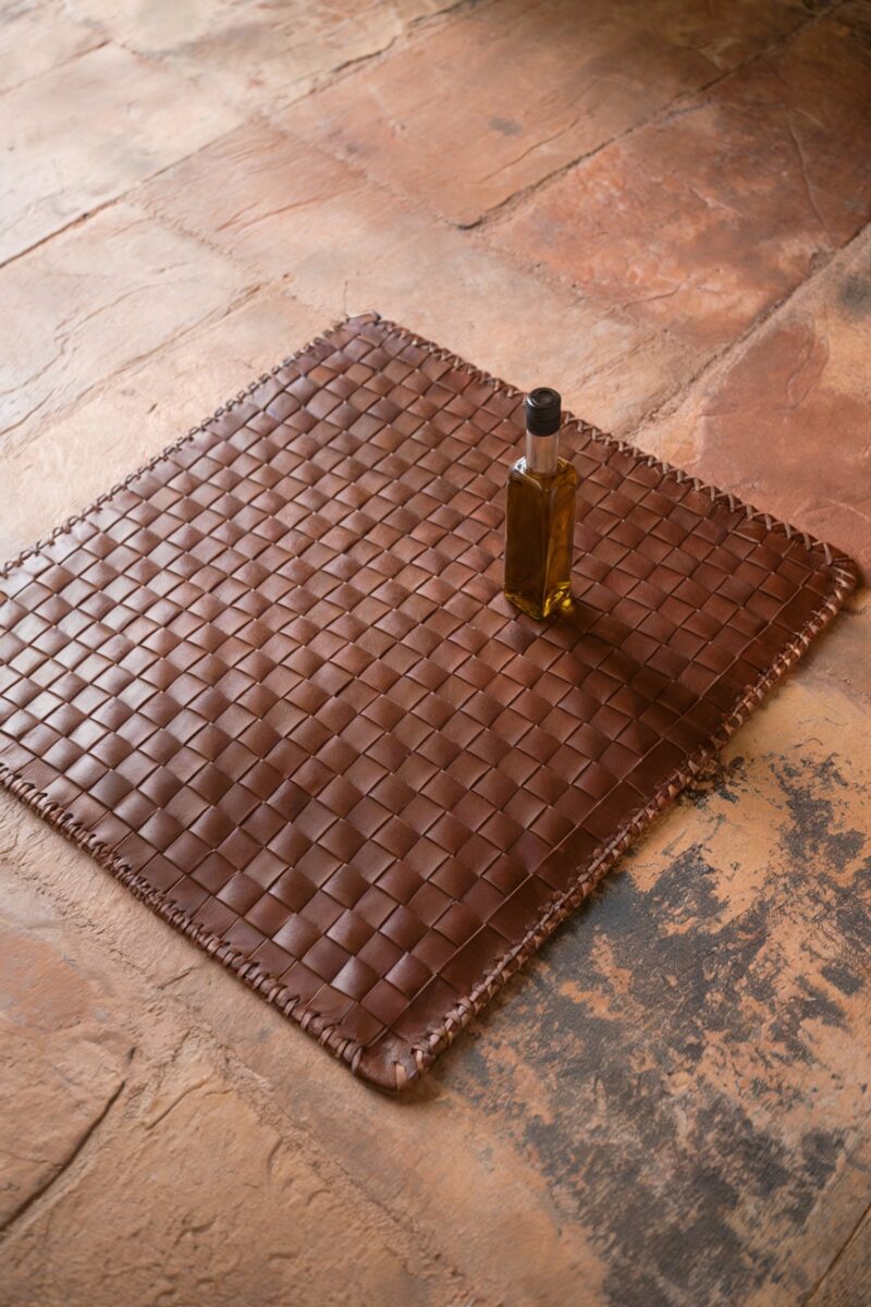 A woven leather mat with a small bottle of oil on top