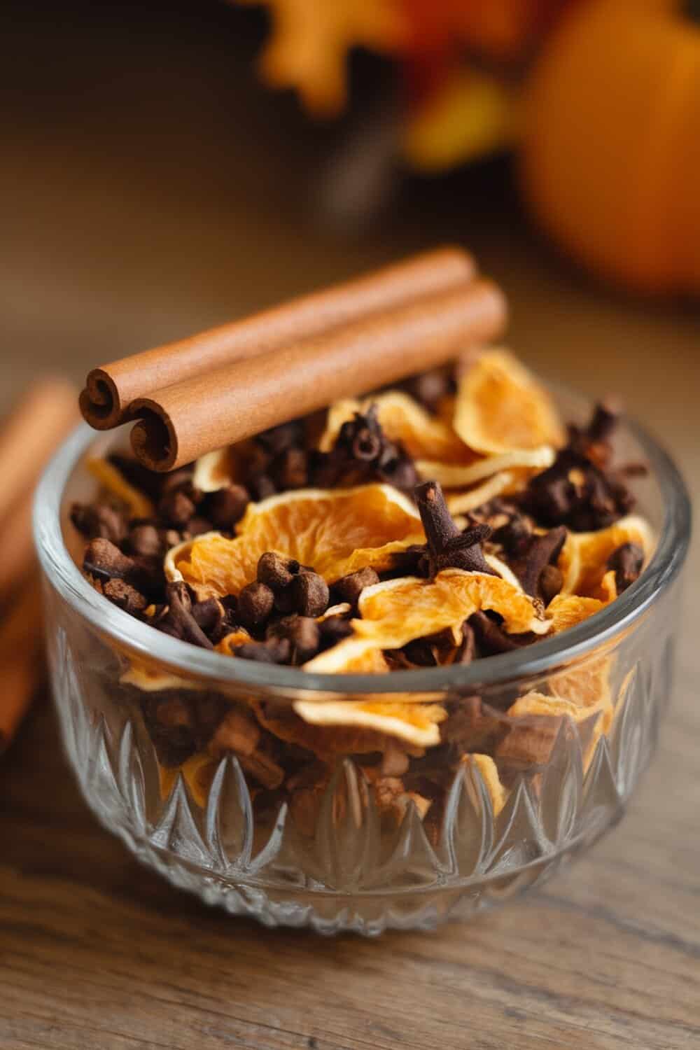 A bowl of pumpkin spice potpourri with dried orange slices, cloves, and cinnamon sticks.