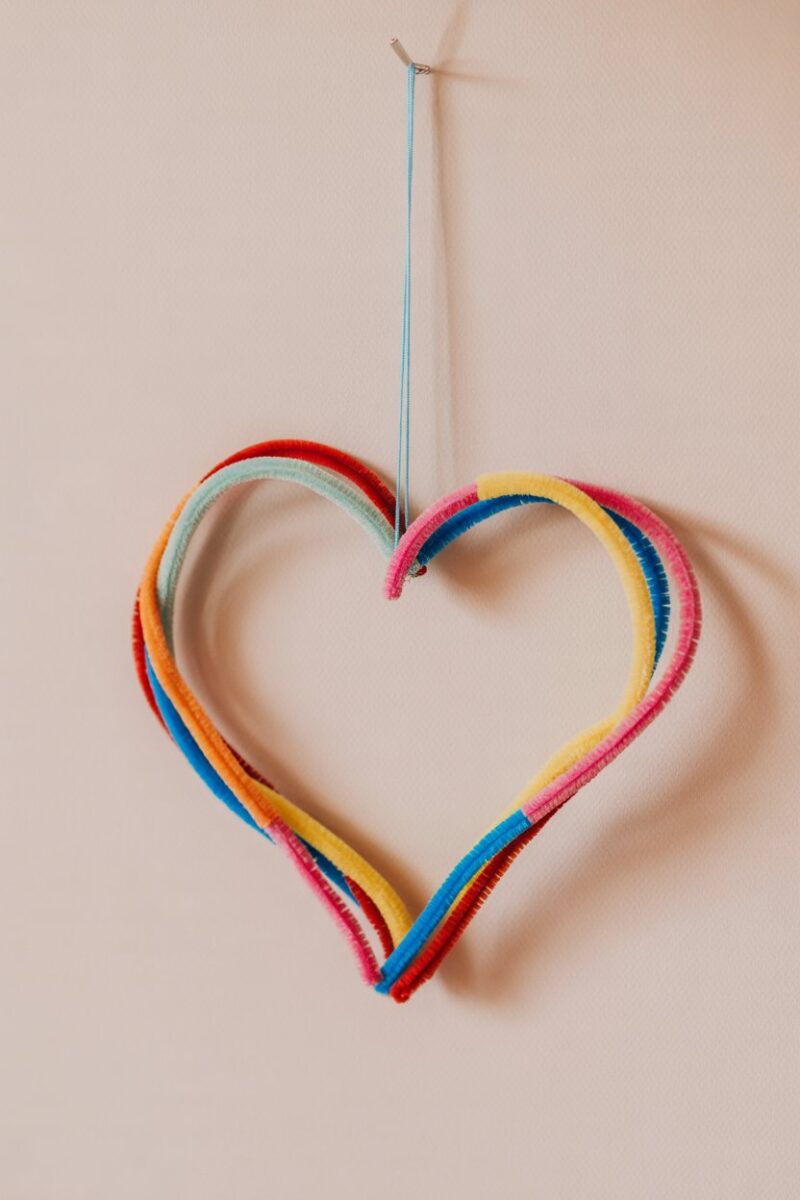 Colorful pipe cleaner wall hanging in the shape of a heart.