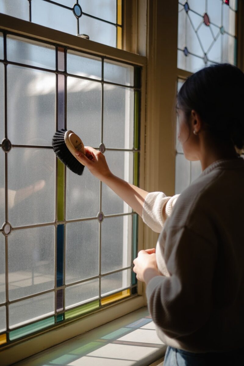 A person cleaning a stained glass window with a brush.