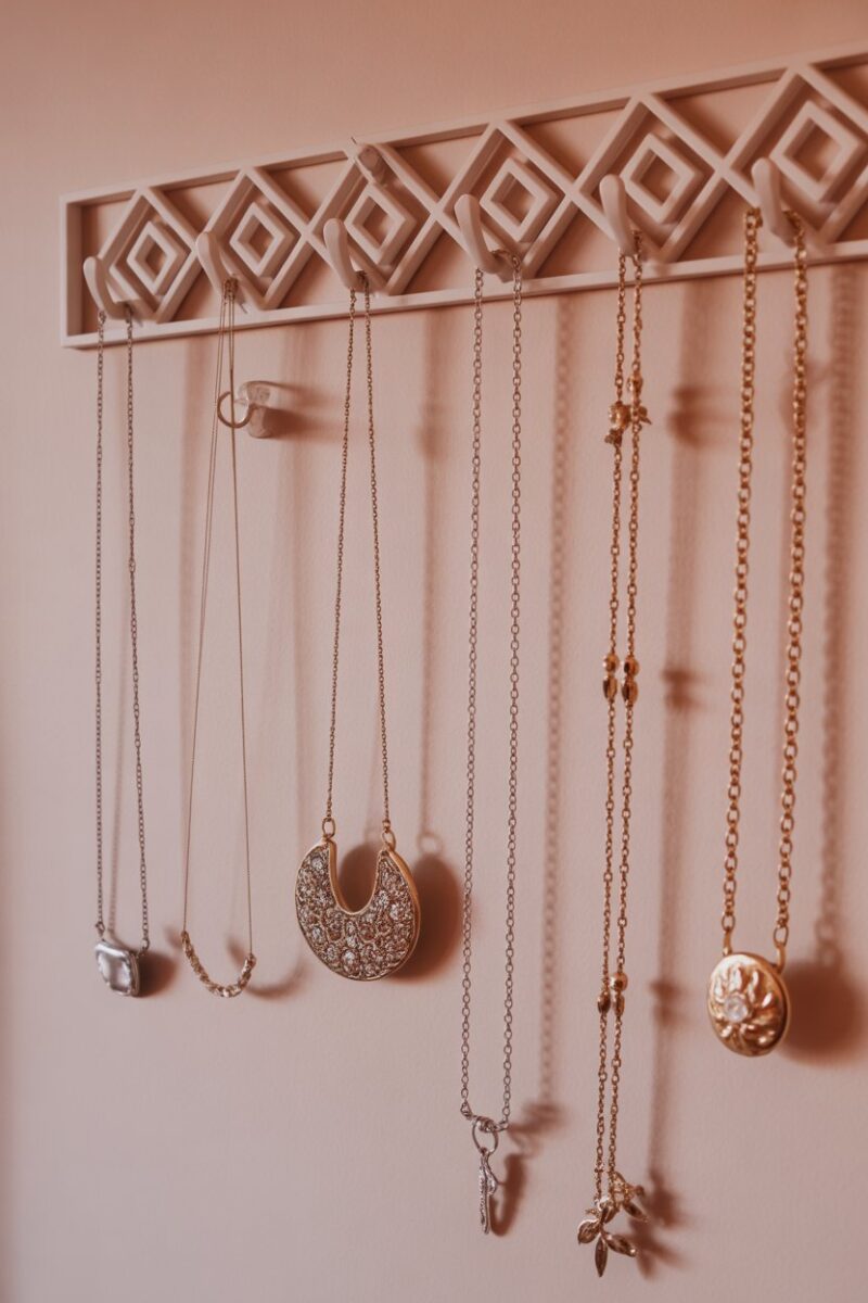 A wall with decorative hooks displaying various necklaces and jewelry.