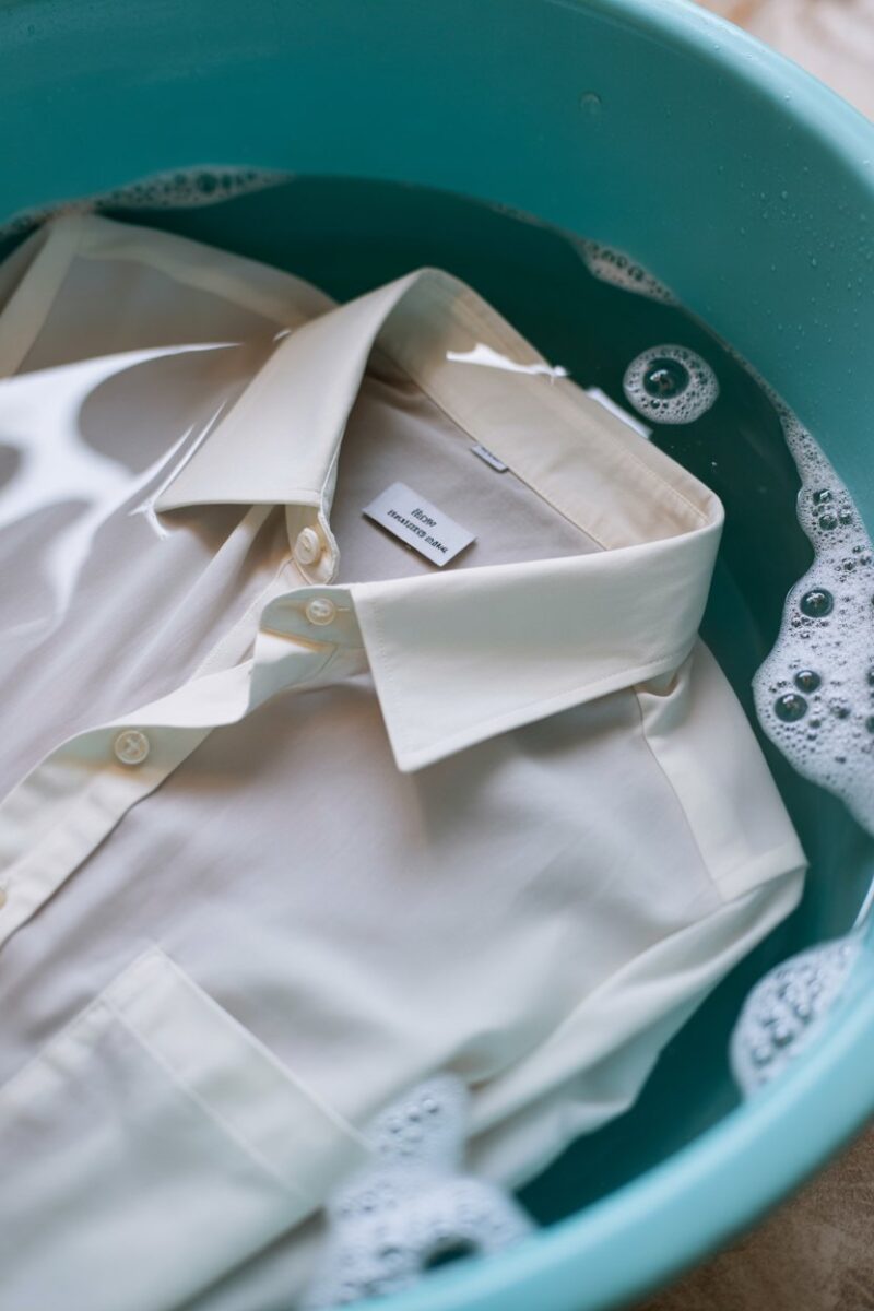 A white shirt soaking in a bowl of water with bubbles.