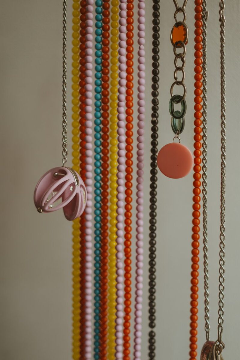 Colorful beaded curtain jewelry holder with various accessories hanging.