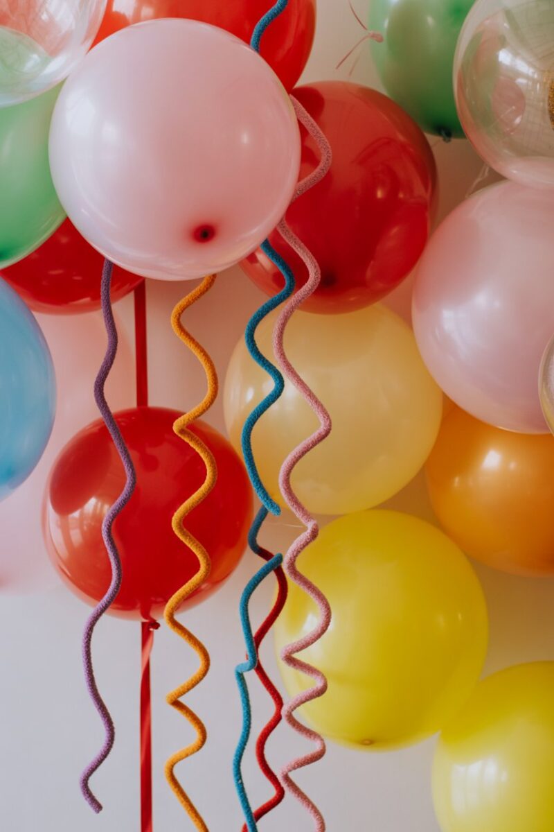 Colorful party decorations with pipe cleaners, balloons, and a festive backdrop.
