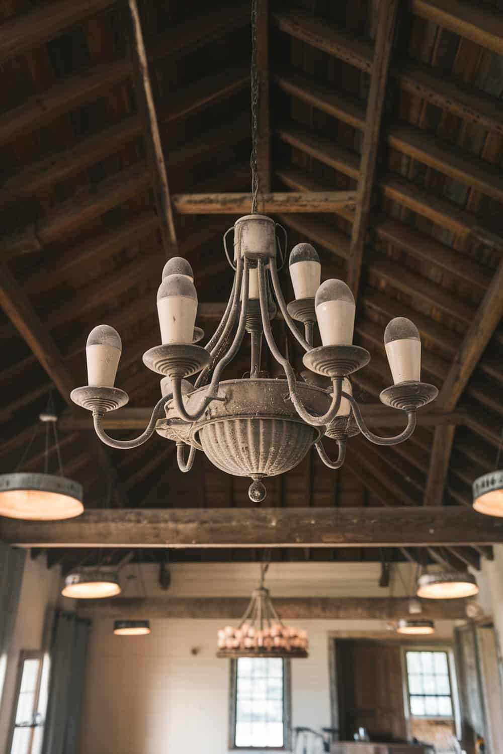 A dusty chandelier hanging from a wooden ceiling.