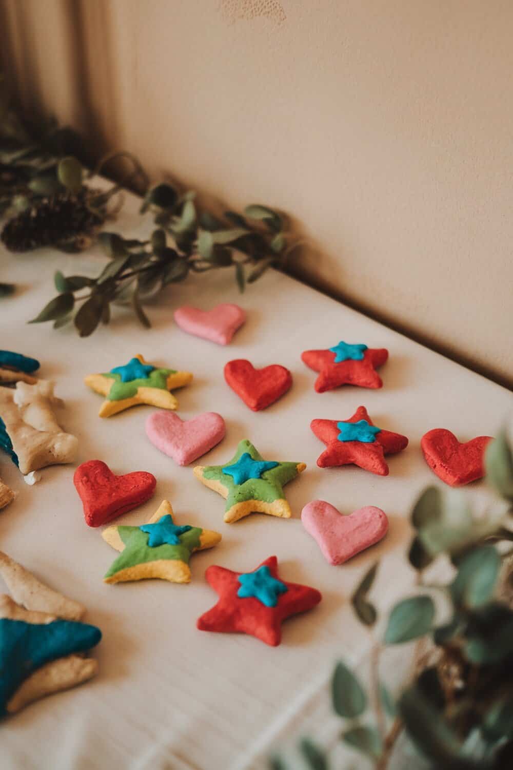 Colorful salt dough ornaments shaped like stars and hearts on a table.