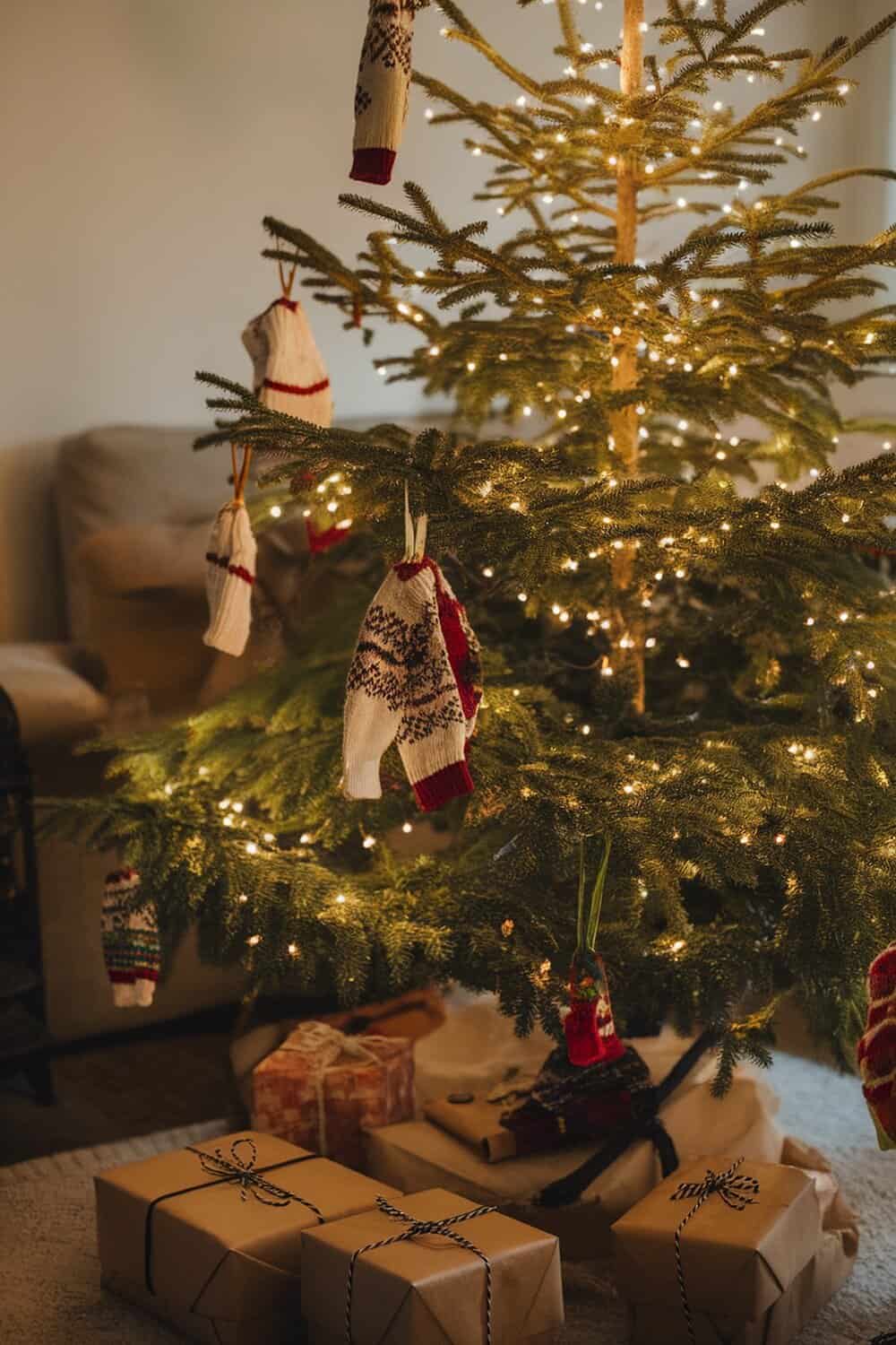 A Christmas tree decorated with upcycled sweater ornaments and wrapped gifts underneath.