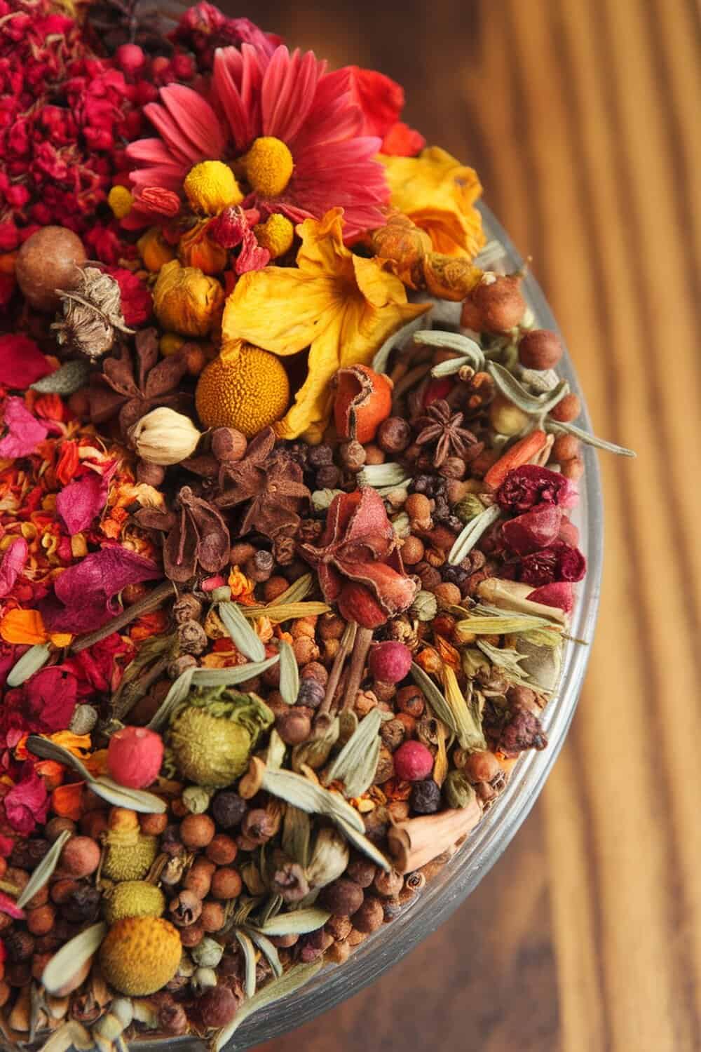 A colorful mix of dried flowers, herbs, and spices in a clear bowl.