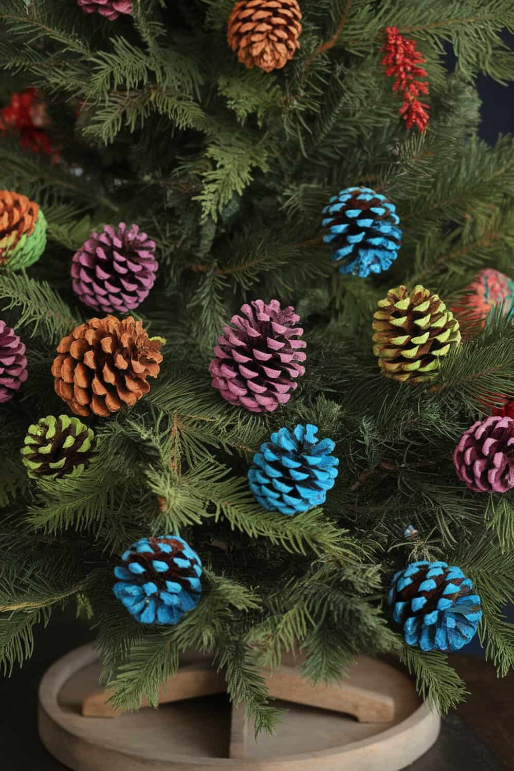 Colorful painted pinecones hanging on a Christmas tree.