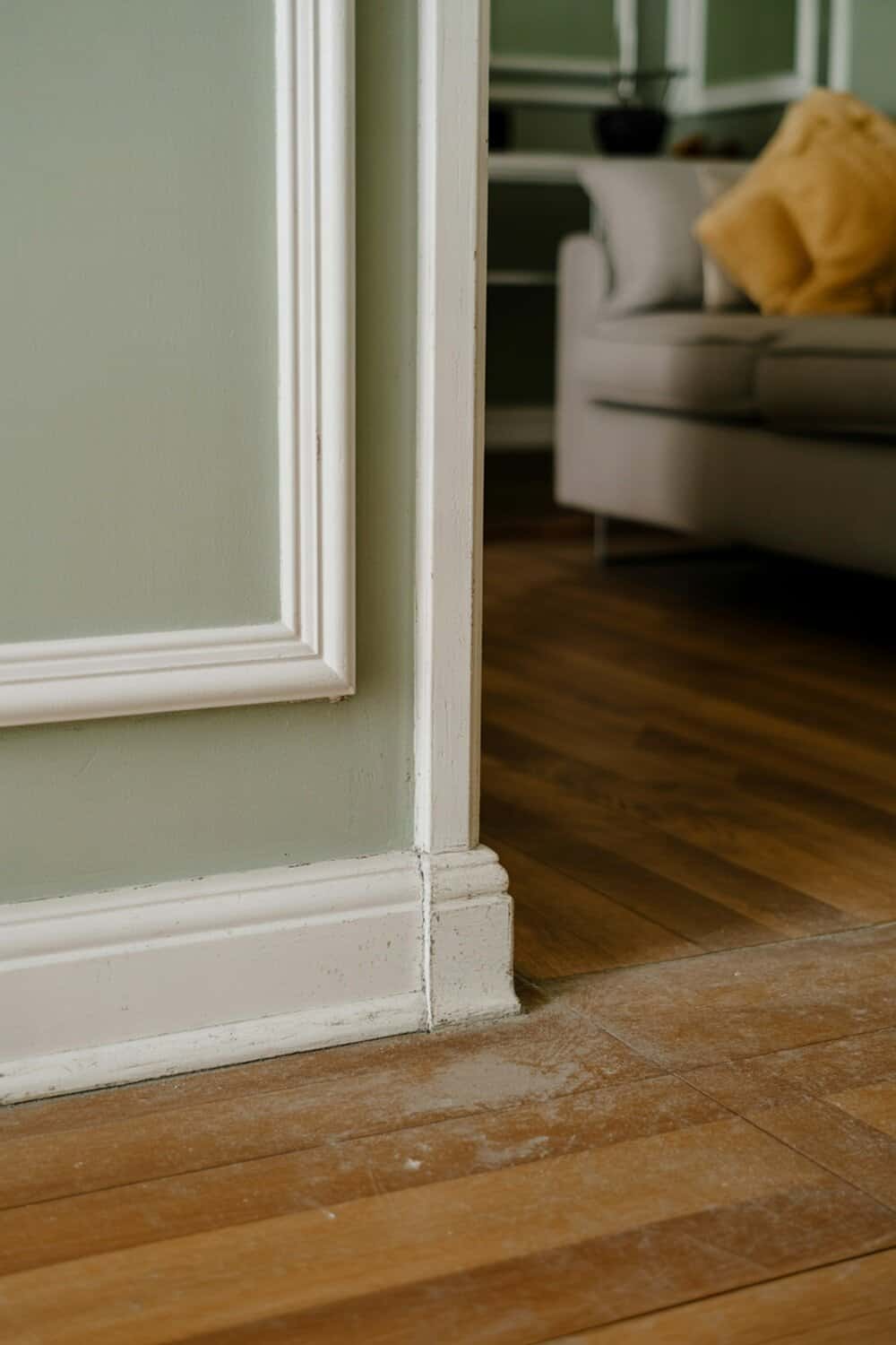 A close-up view of baseboards and wooden flooring, showing dust accumulation.
