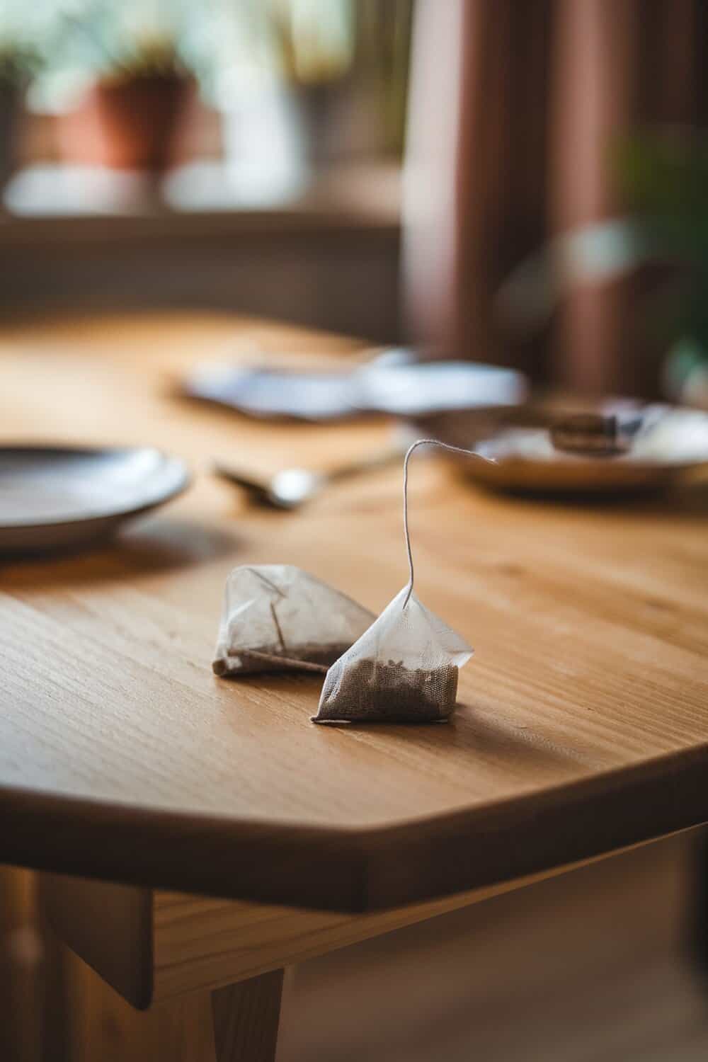 Two tea bags on a wooden table with a blurred background