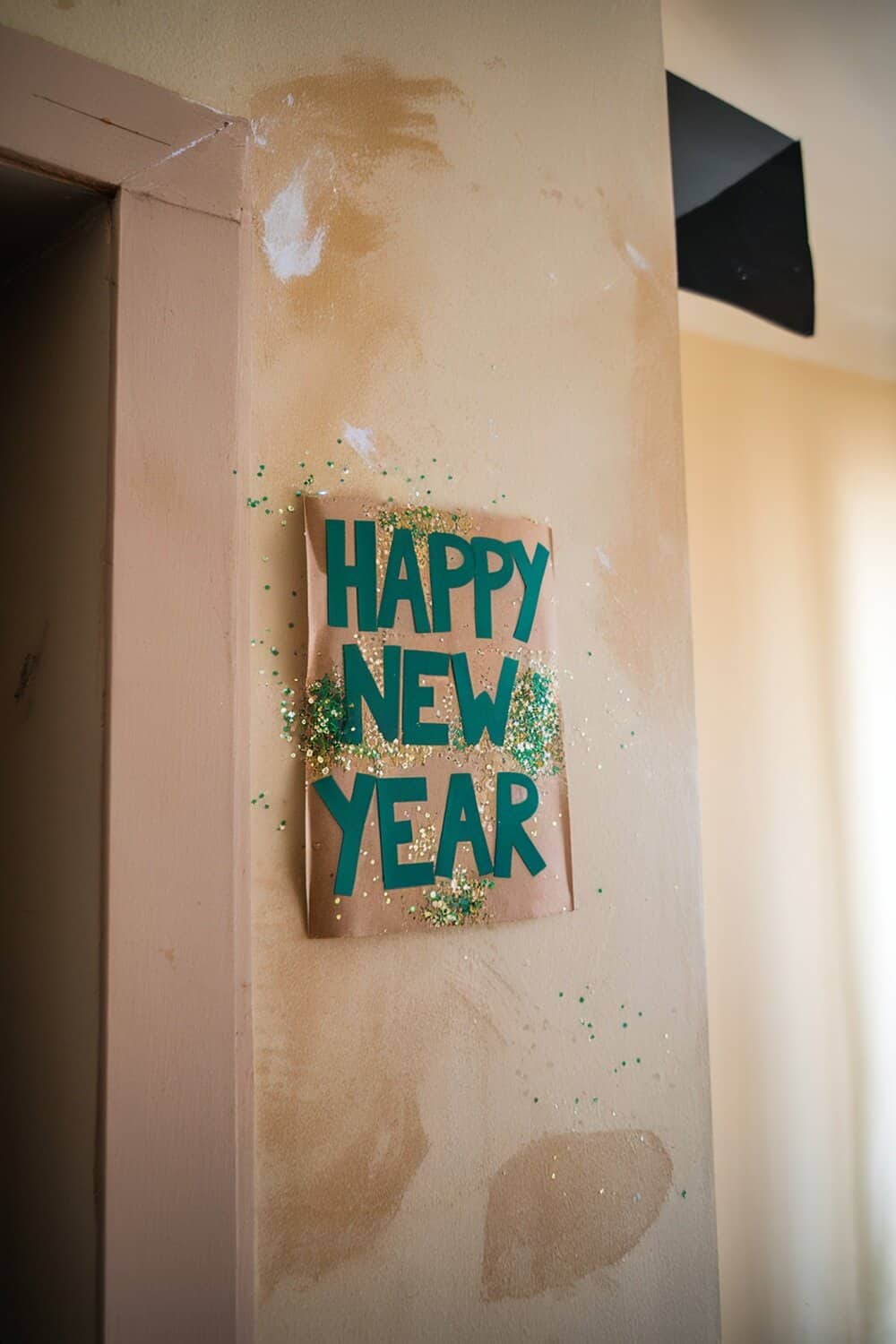 A DIY glittery New Year sign that reads 'HAPPY NEW YEAR' with sparkling decorations.
