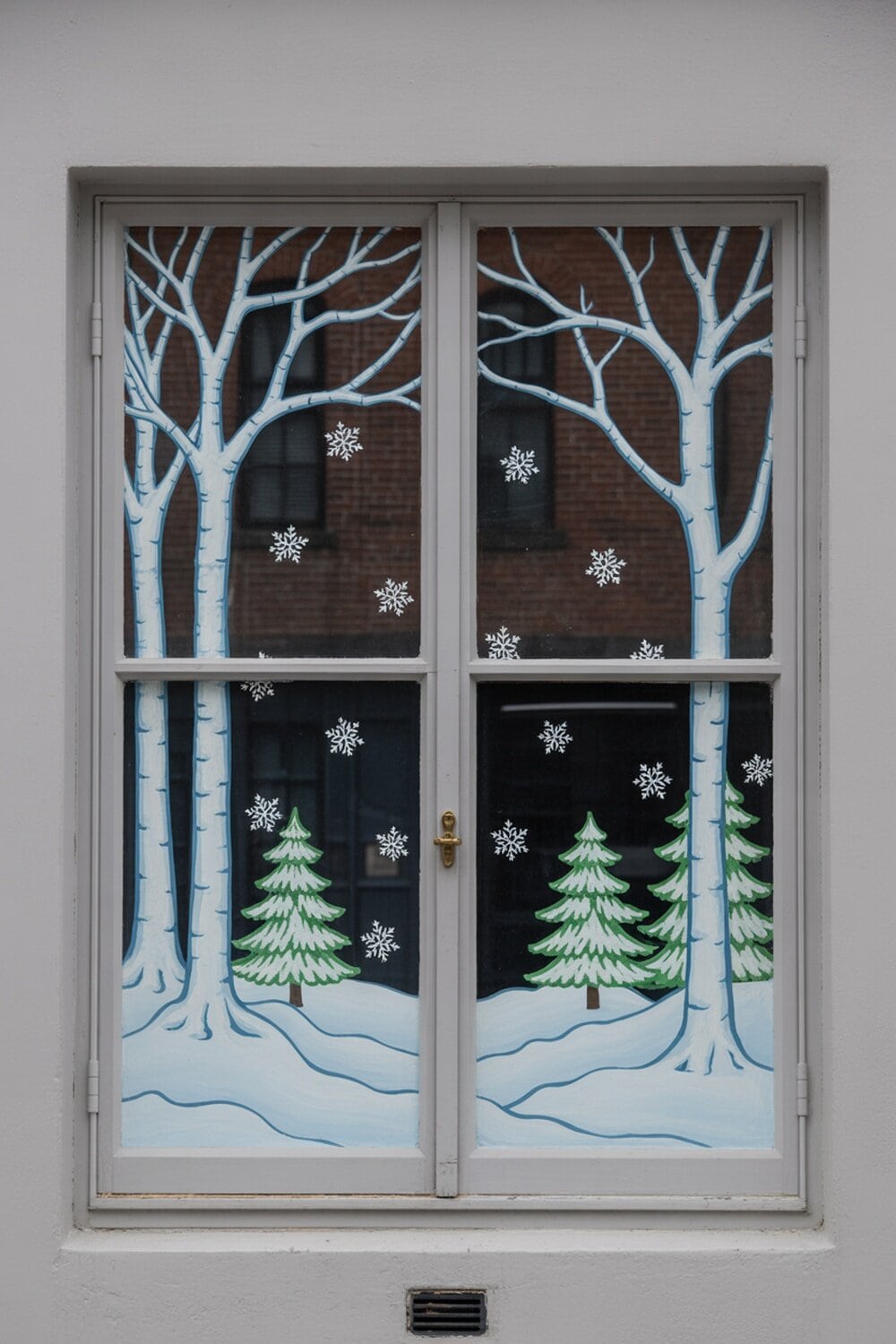 A window mural featuring snowy trees and snowflakes, creating a winter scene.