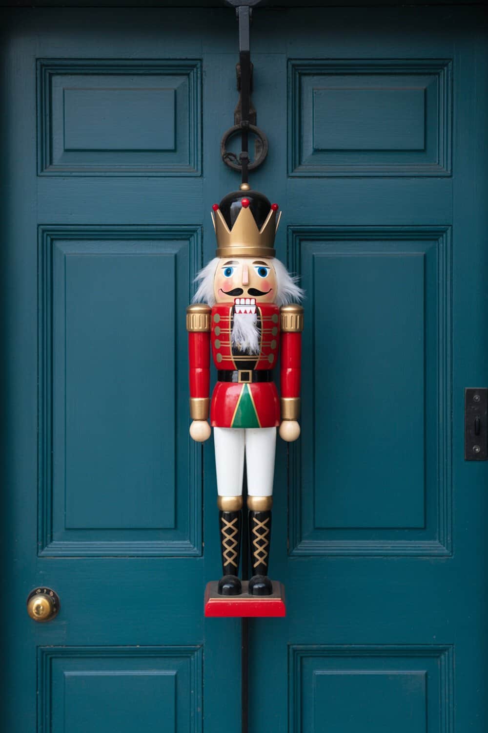 A nutcracker decoration hanging on a teal door