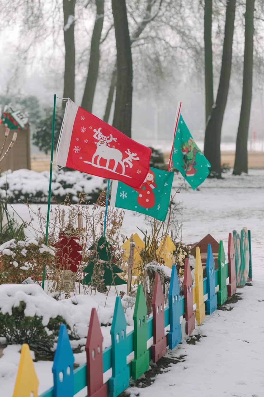 Colorful garden flags with Christmas designs in a snowy garden