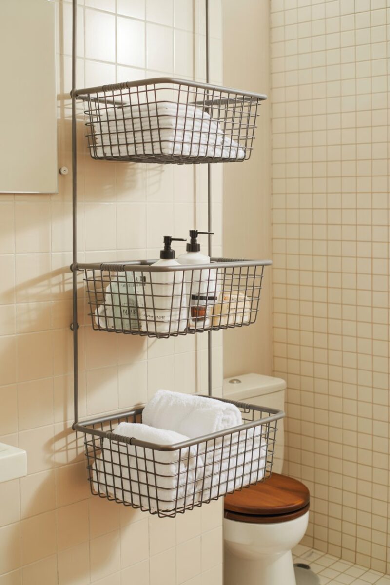 A bathroom with hanging wire baskets storing towels and toiletries.