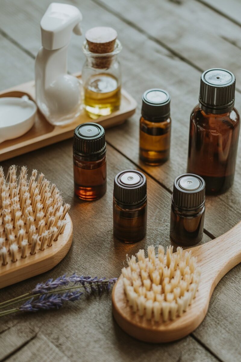 A collection of essential oils and cleaning brushes arranged on a wooden surface.