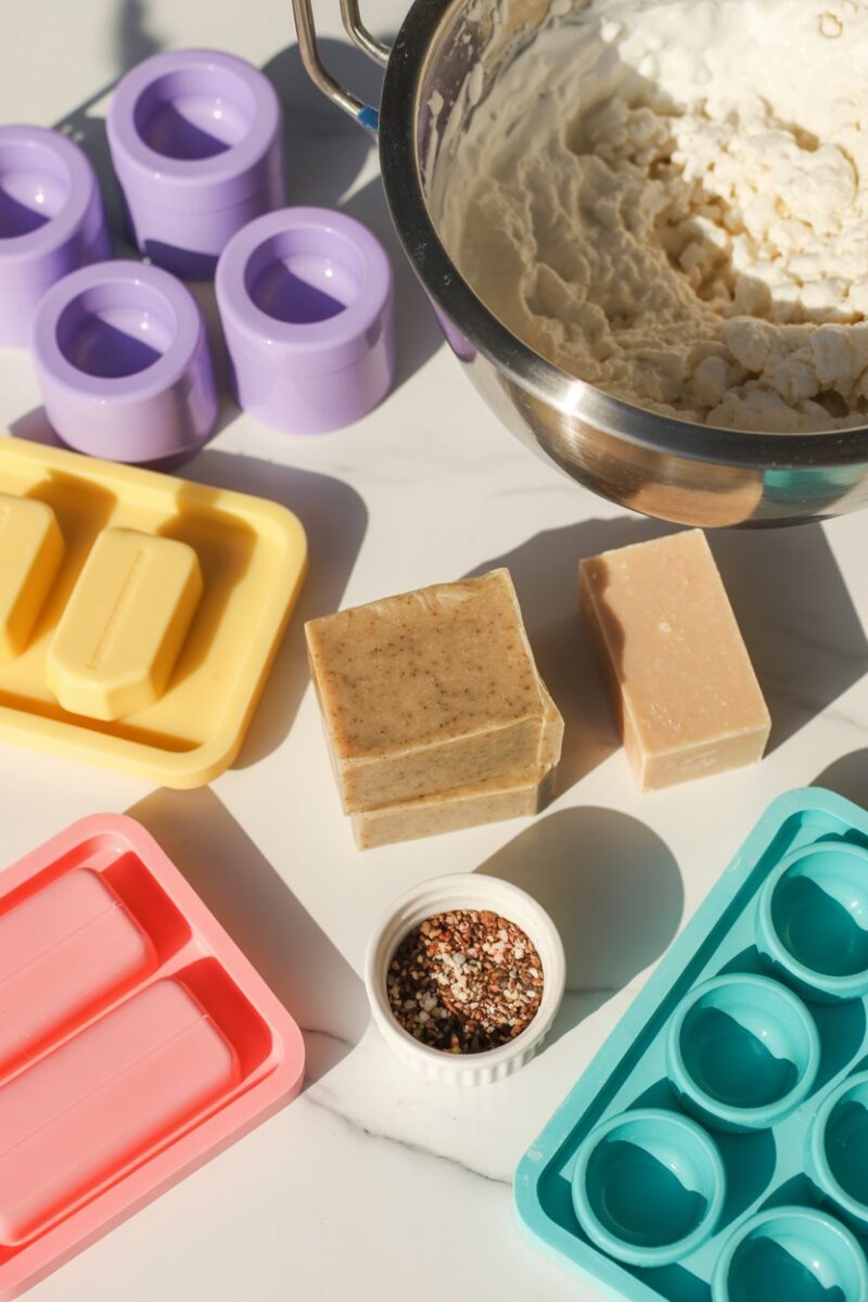 A colorful arrangement of soap making supplies including molds, soap bars, and a mixing bowl.