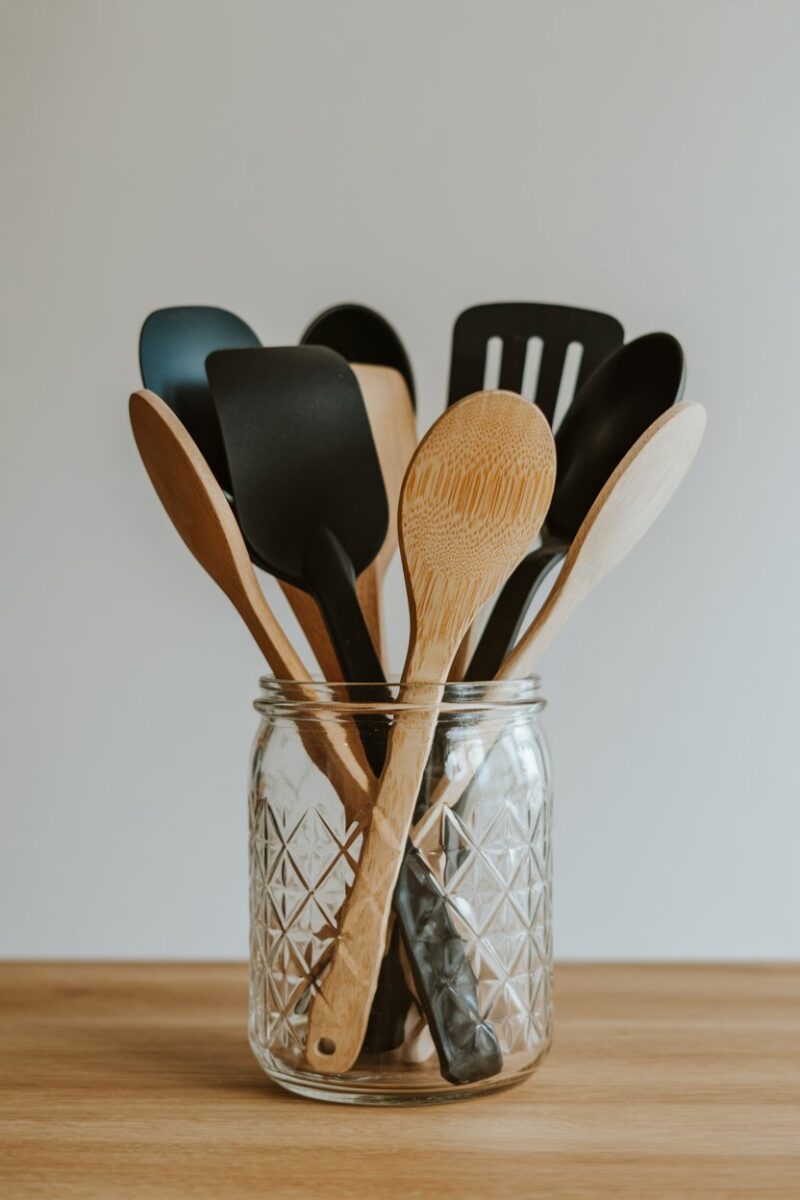 A glass jar filled with various kitchen utensils like spatulas and wooden spoons.