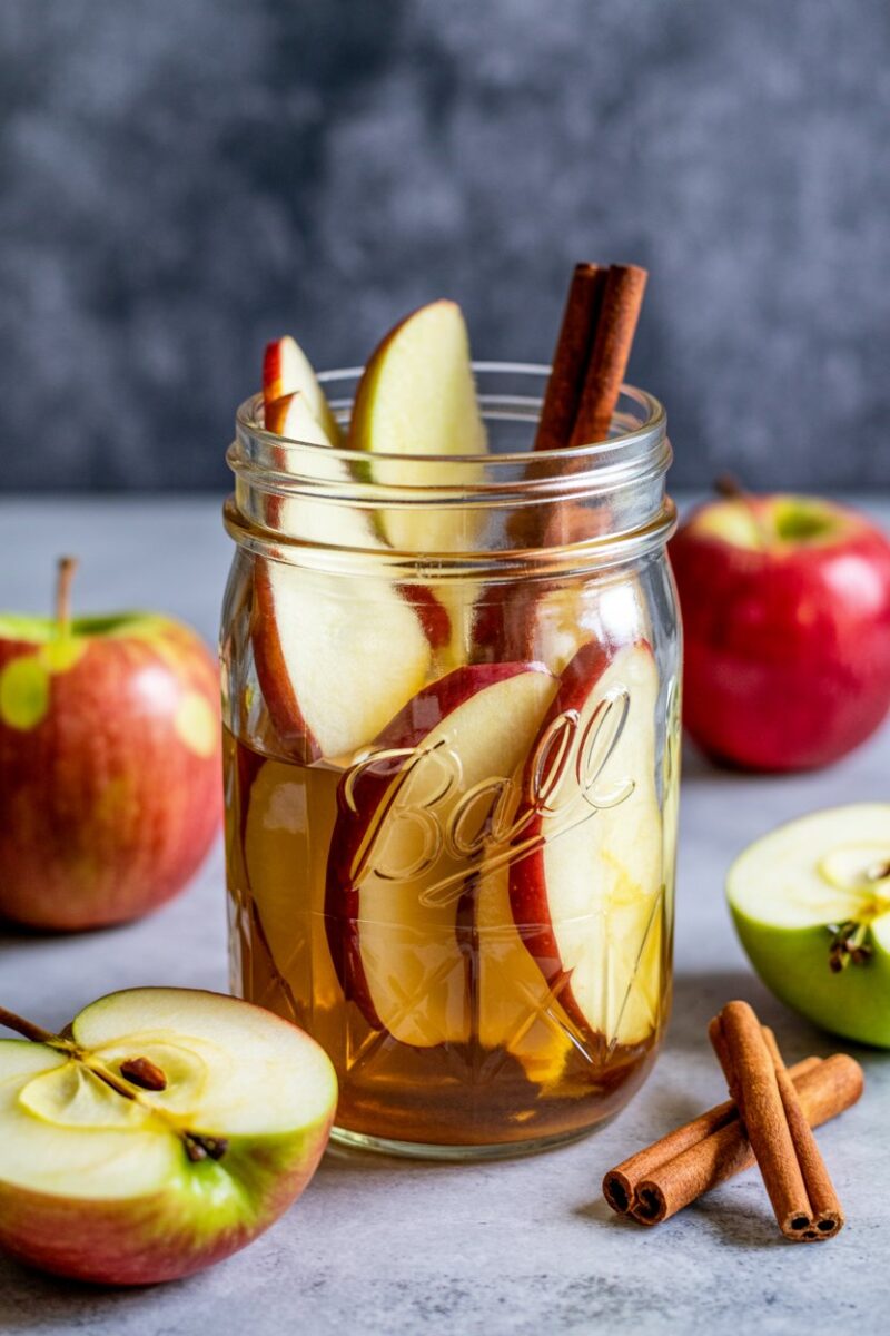 A jar filled with apple slices and cinnamon sticks.