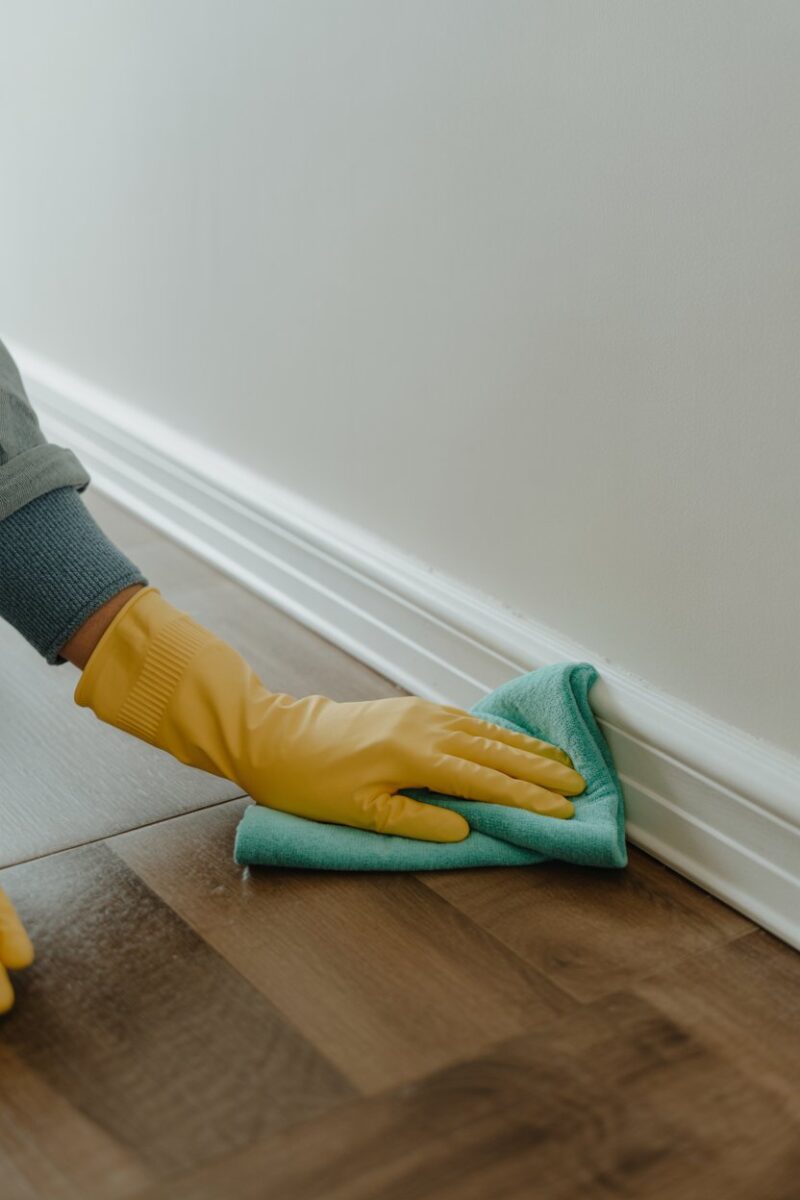 A person cleaning baseboards with a cloth