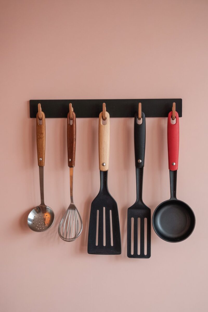 Magnetic strip holding various kitchen utensils on a wall.