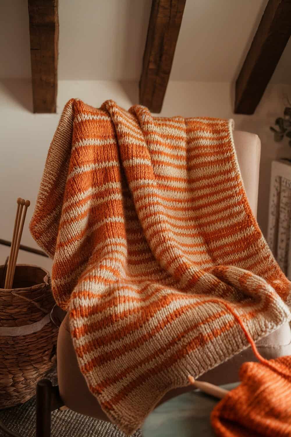 A cozy orange and cream striped knit scarf draped over a chair.