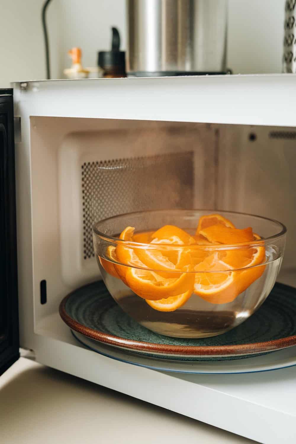 A bowl of orange peels in water inside a microwave.