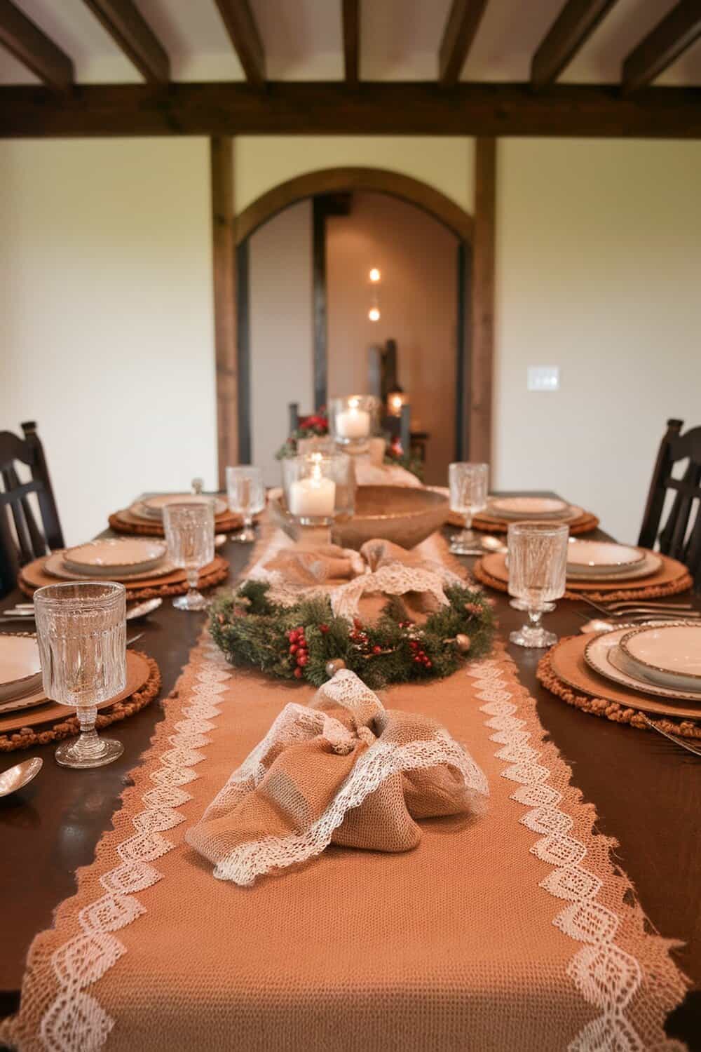 A beautifully set dining table featuring burlap and lace accents, with a wreath and candles.