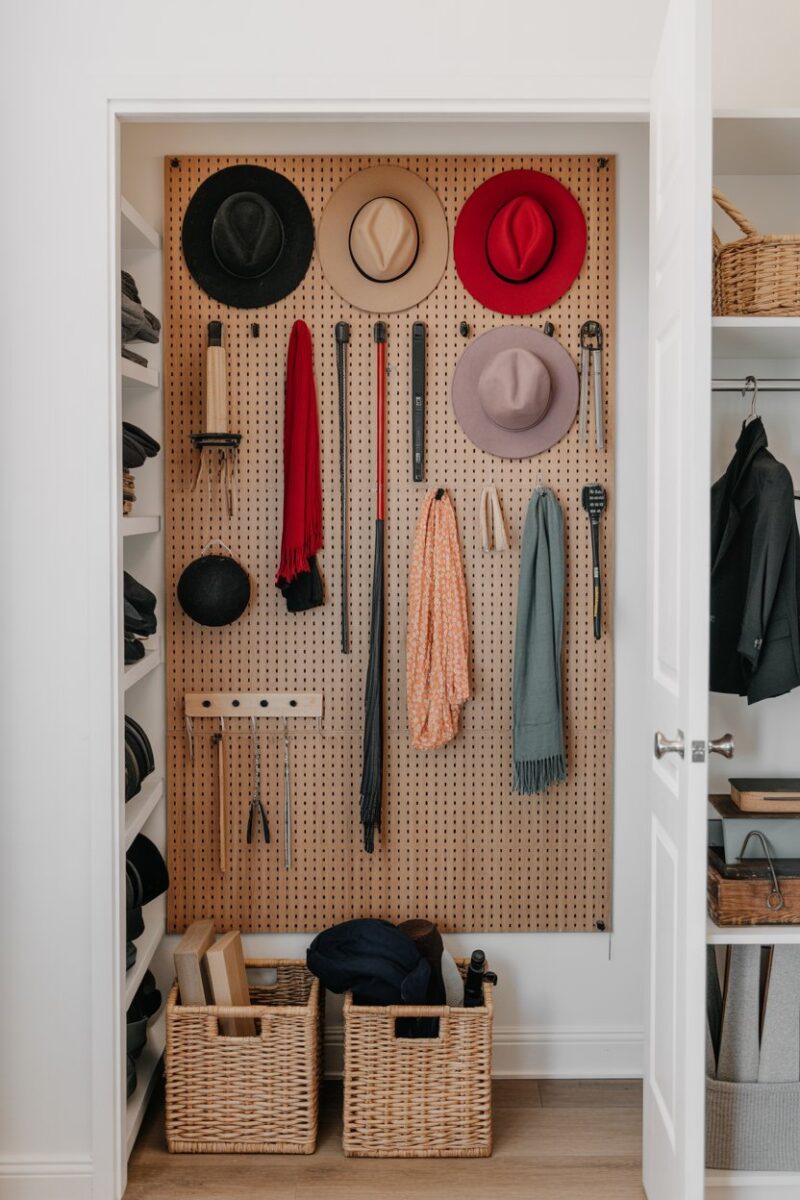 A closet with a pegboard wall displaying hats, scarves, and tools for organized storage.